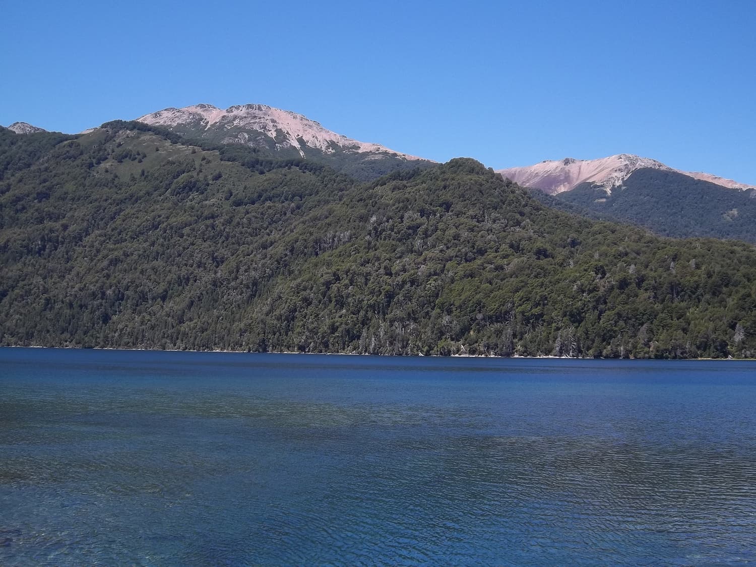 The deep blue Lago Correntoso under forested mountains on the Seven Lakes Road