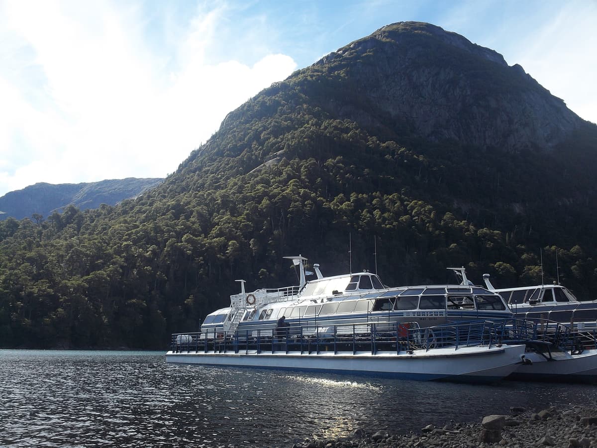 A tourist catamaran moored at Puerto Blest beneath forested mountains