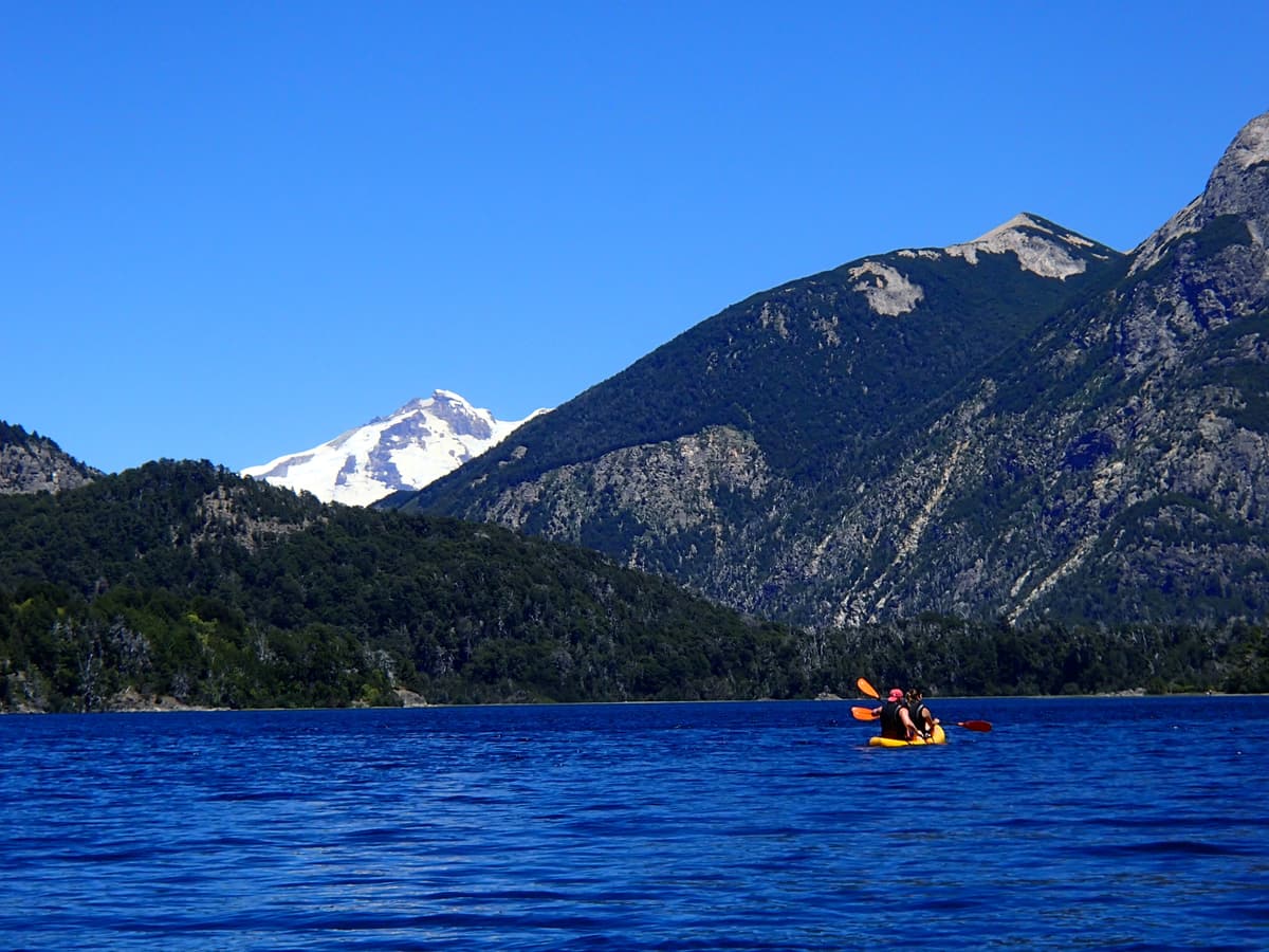 A kayak on the deep blue Lago Perito Moreno with a snowy peak behind